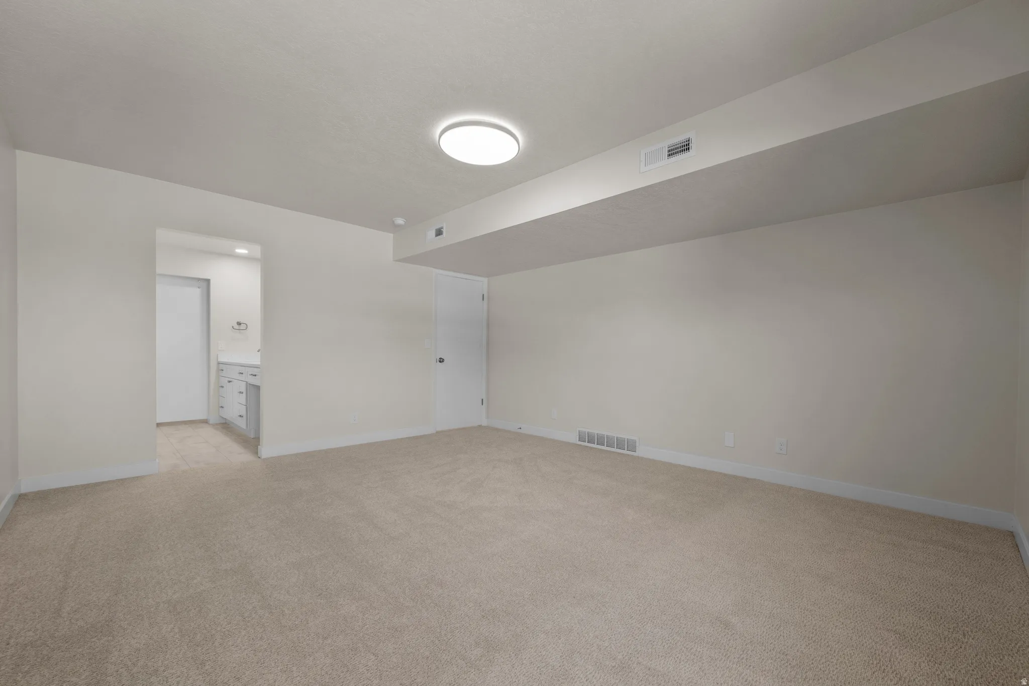 Open room with plush carpeting, recessed lighting, and a white interior door