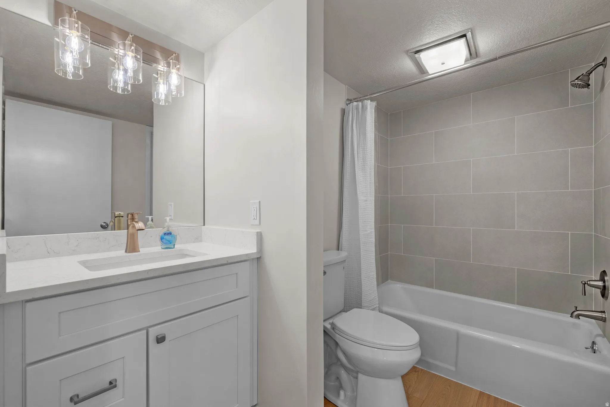 Bathroom featuring a white vanity with a light-colored quartz countertop, a large mirror, and a modern light fixture