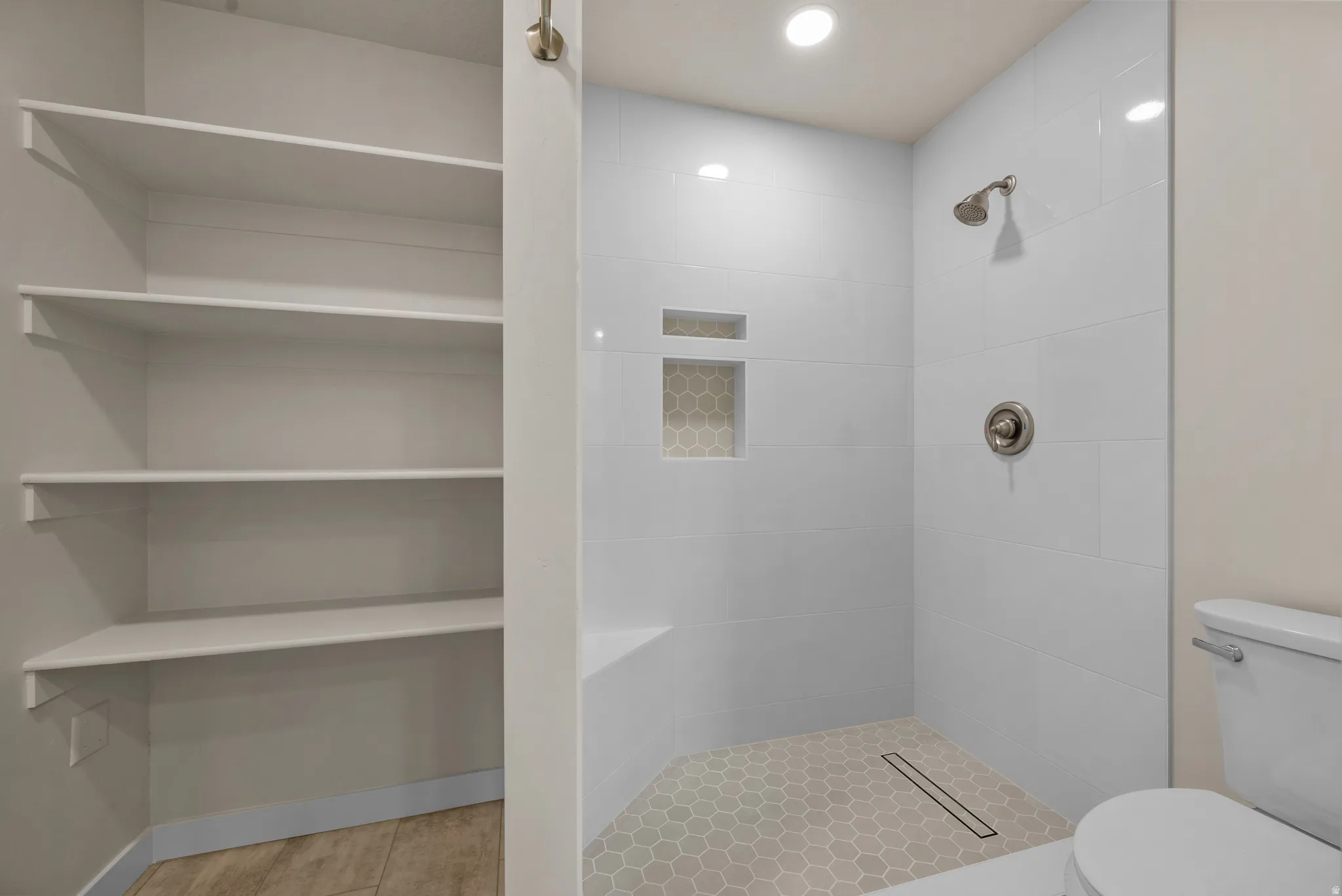 Walk-in shower with white subway tile, a built-in bench, and a recessed niche featuring hexagonal accent tile