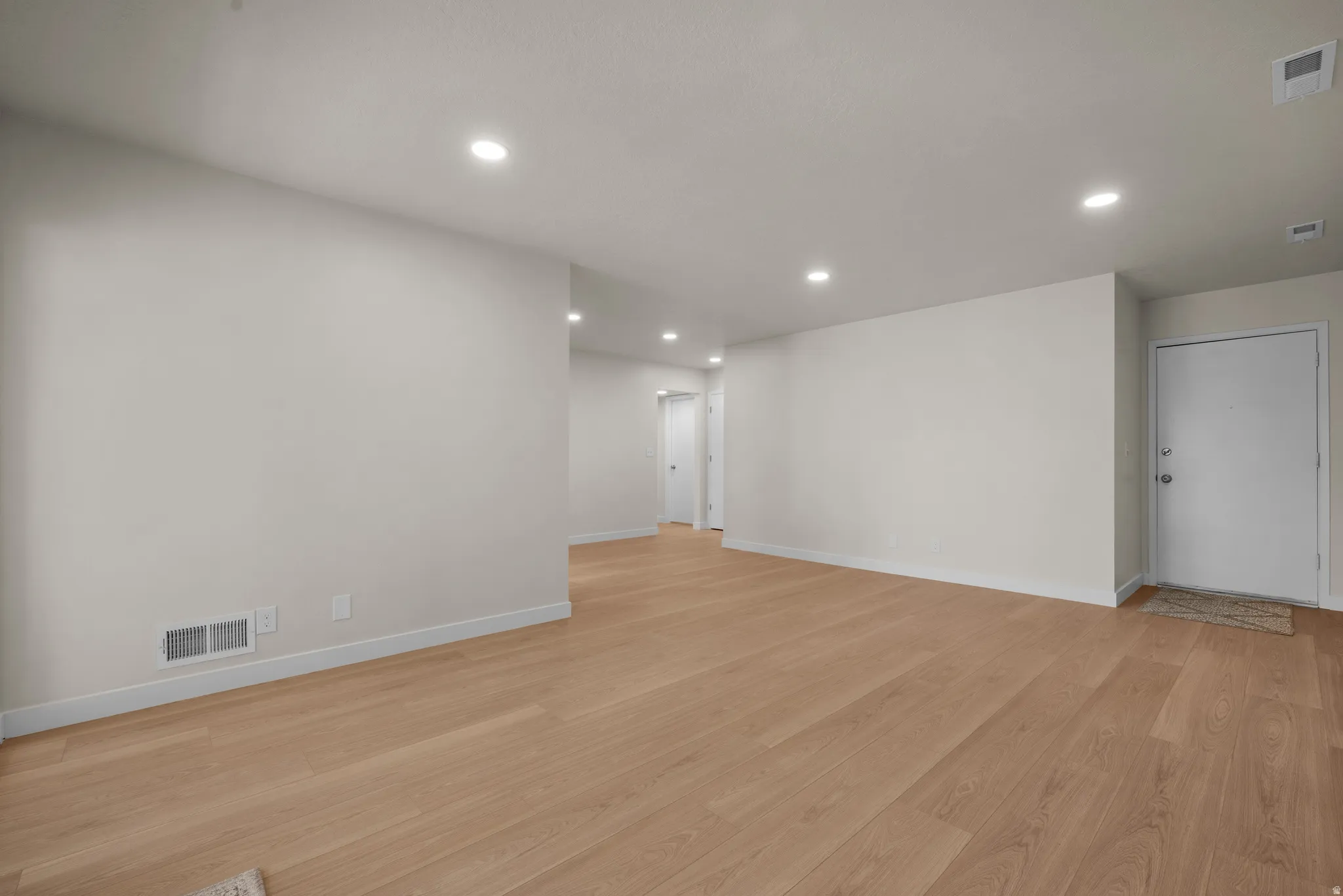 Open-concept living area featuring wood-finish flooring, recessed lighting, and crisp white walls