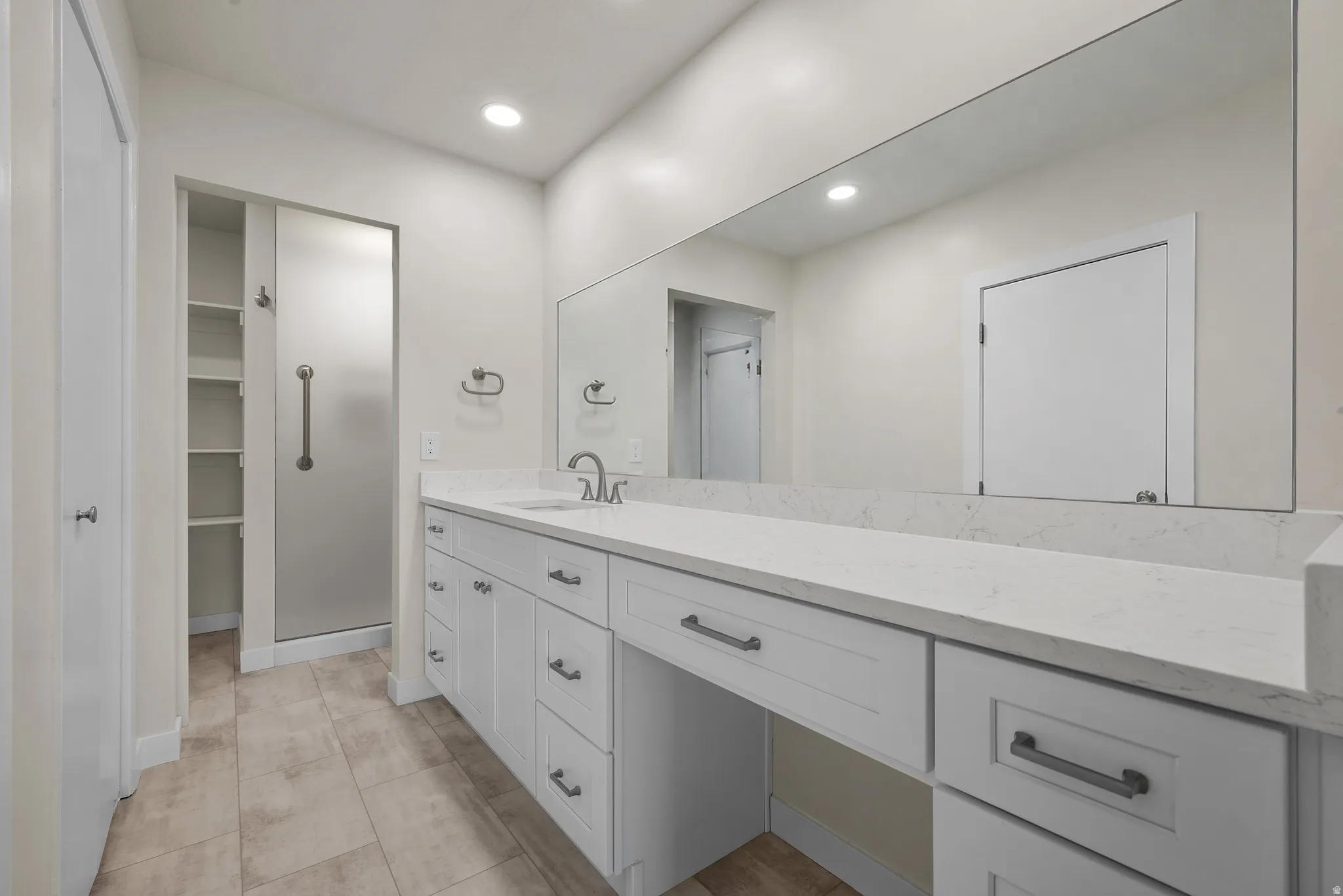 Spacious bathroom featuring an extended vanity, quartz countertops, and white cabinetry
