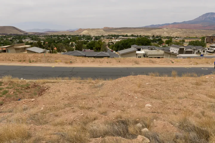 Expansive desert landscape with a paved road and distant residential structures