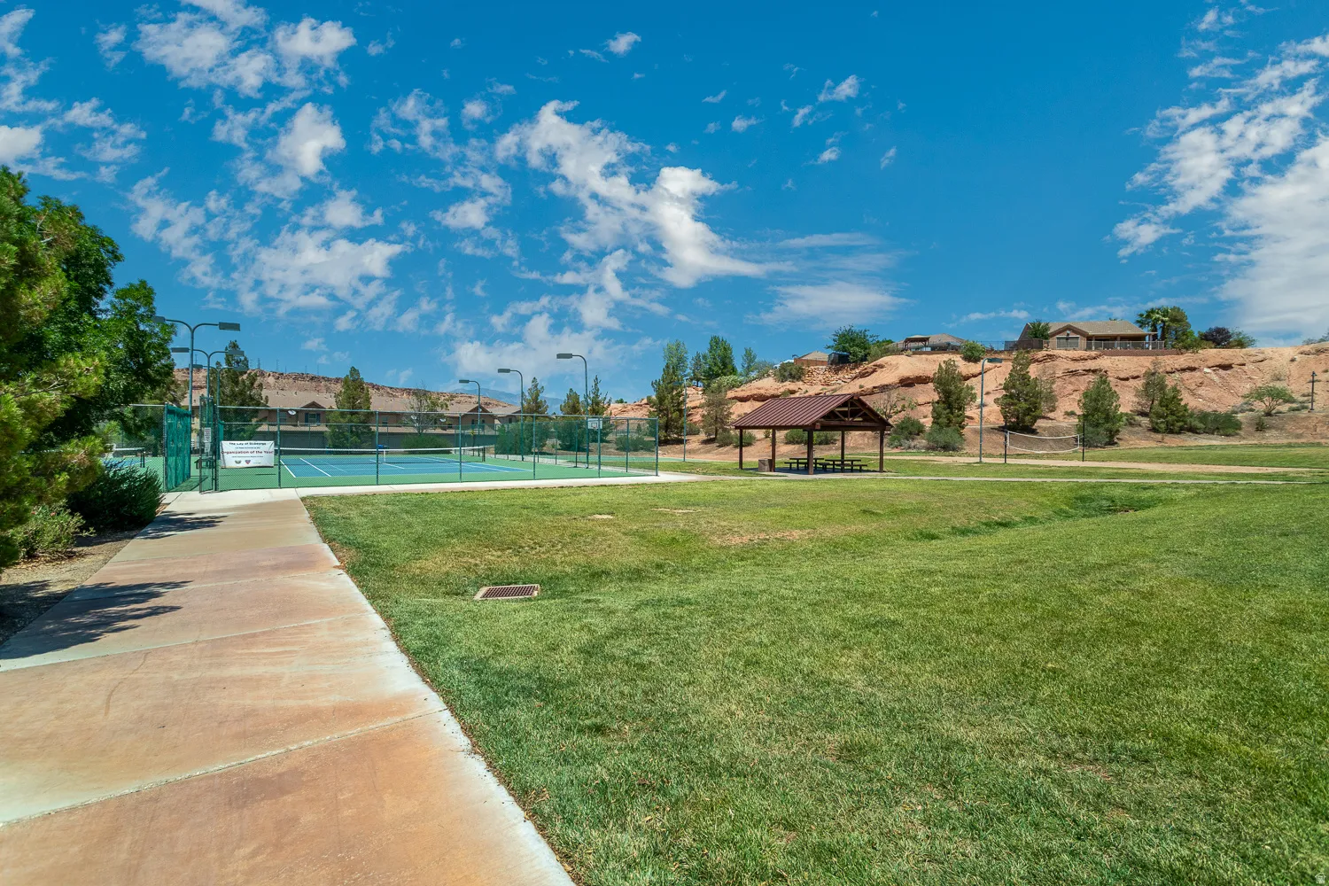 Community tennis courts with light standards, covered picnic area, and expansive green space