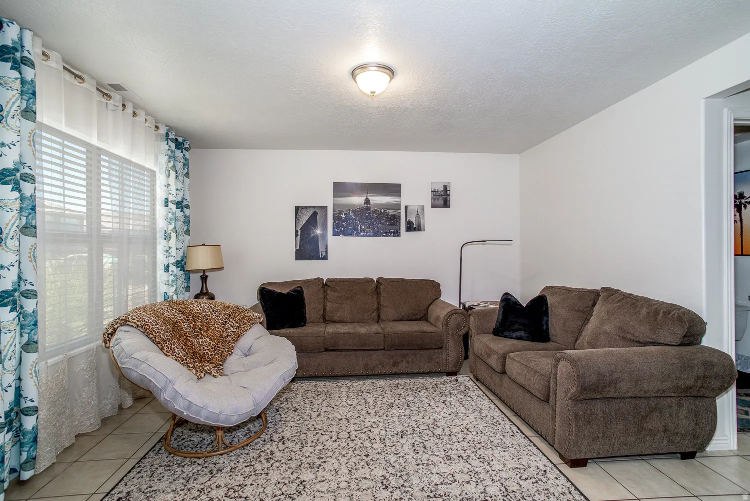 Bright living space featuring a window with horizontal blinds and decorative curtains