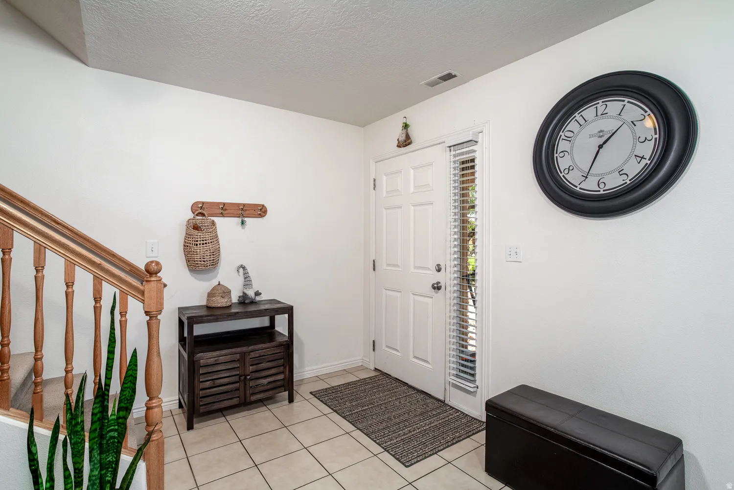 Entryway featuring tile flooring, a white paneled door with a sidelight, and wood-finish stair railings