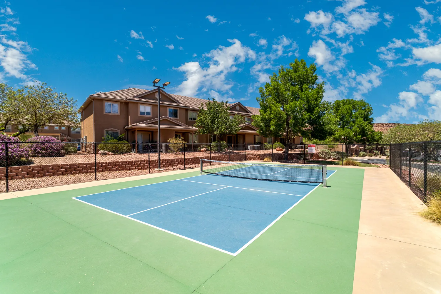 Recreational court with a blue and green surface, surrounded by black chain-link fencing