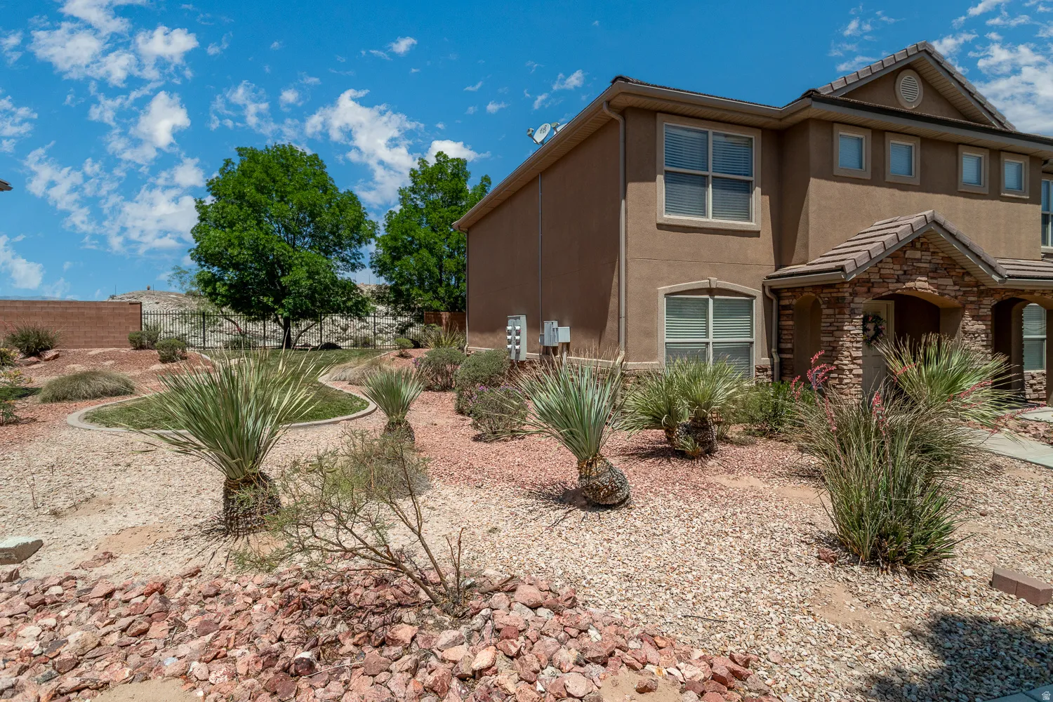 Stucco exterior with a stone veneer entry, arched doorway, and multi-pane windows