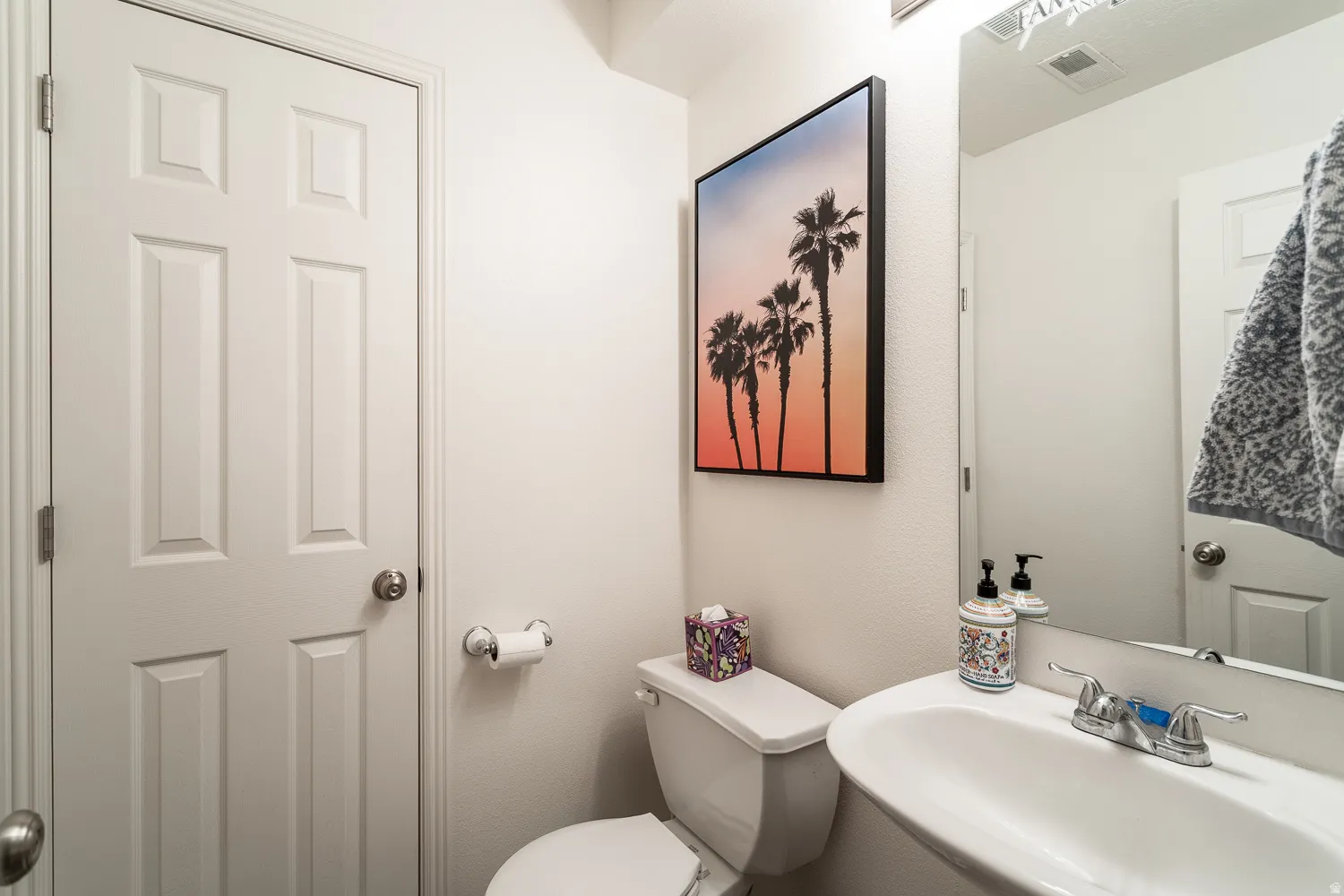 Compact powder room featuring a pedestal sink with a chrome faucet
