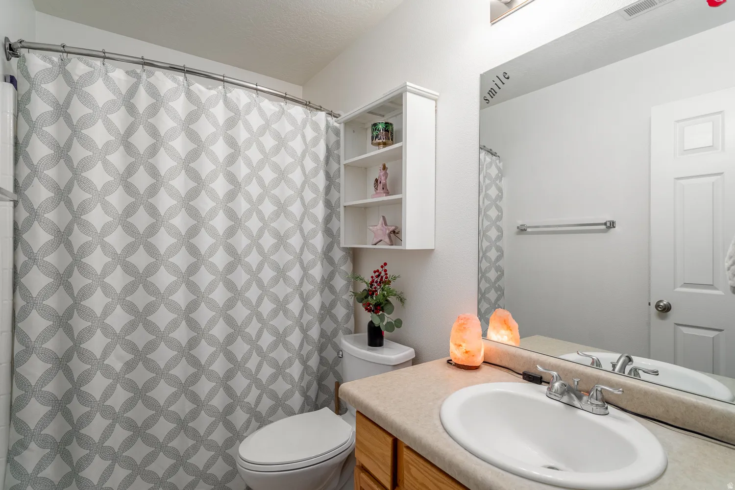 Bathroom featuring a single vanity with laminate countertop, built-in medicine cabinet, and a shower-tub combination with a curved rod