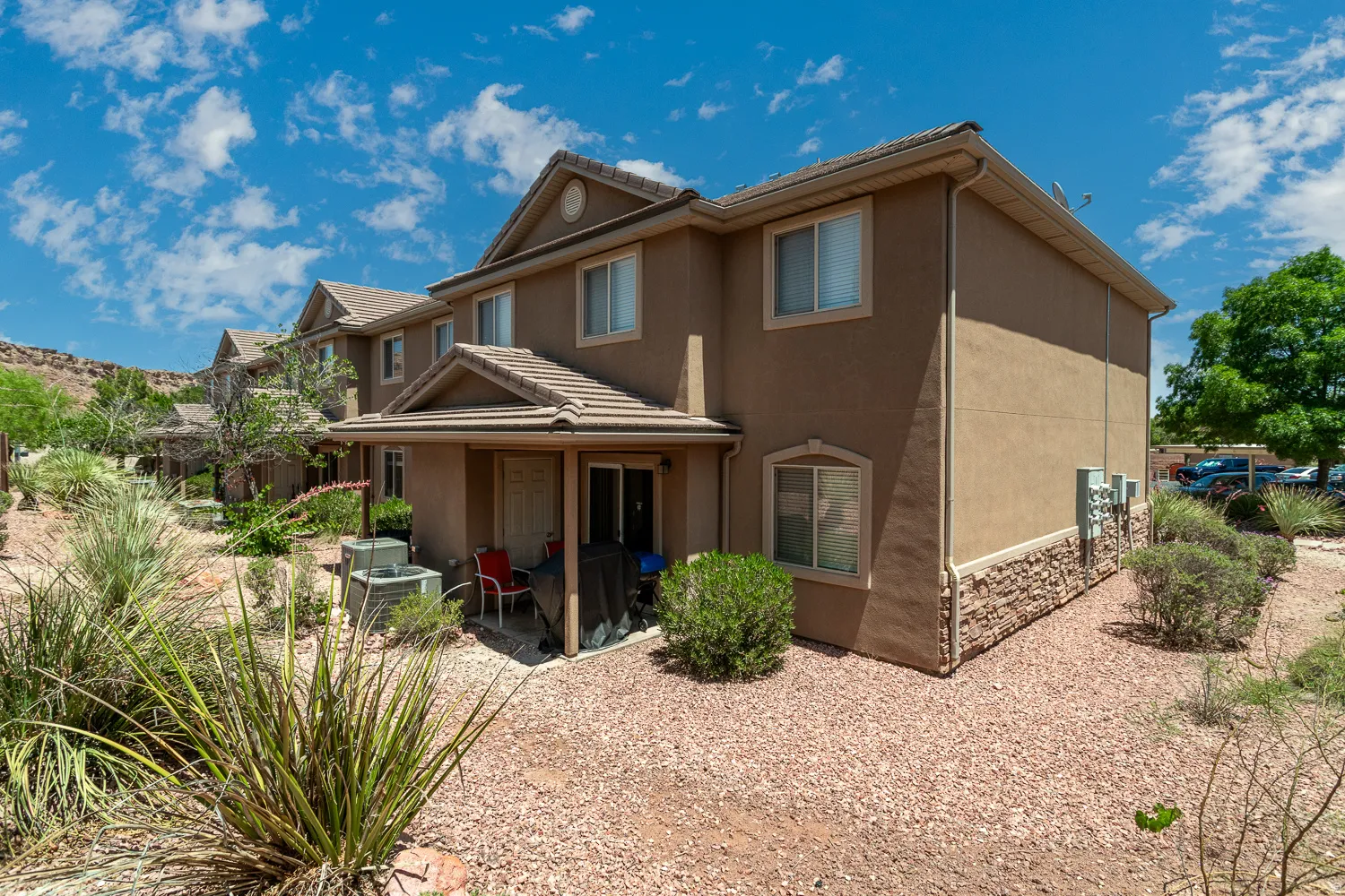 Two-story stucco exterior featuring a covered patio and stone veneer accents