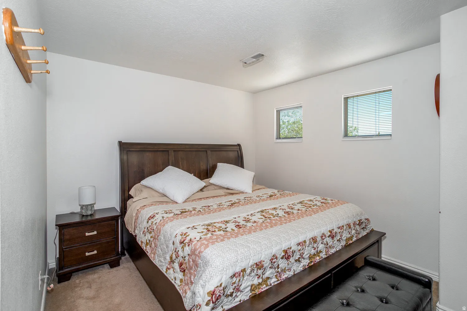 Neutral wall paint, two windows with blinds, and carpeted flooring