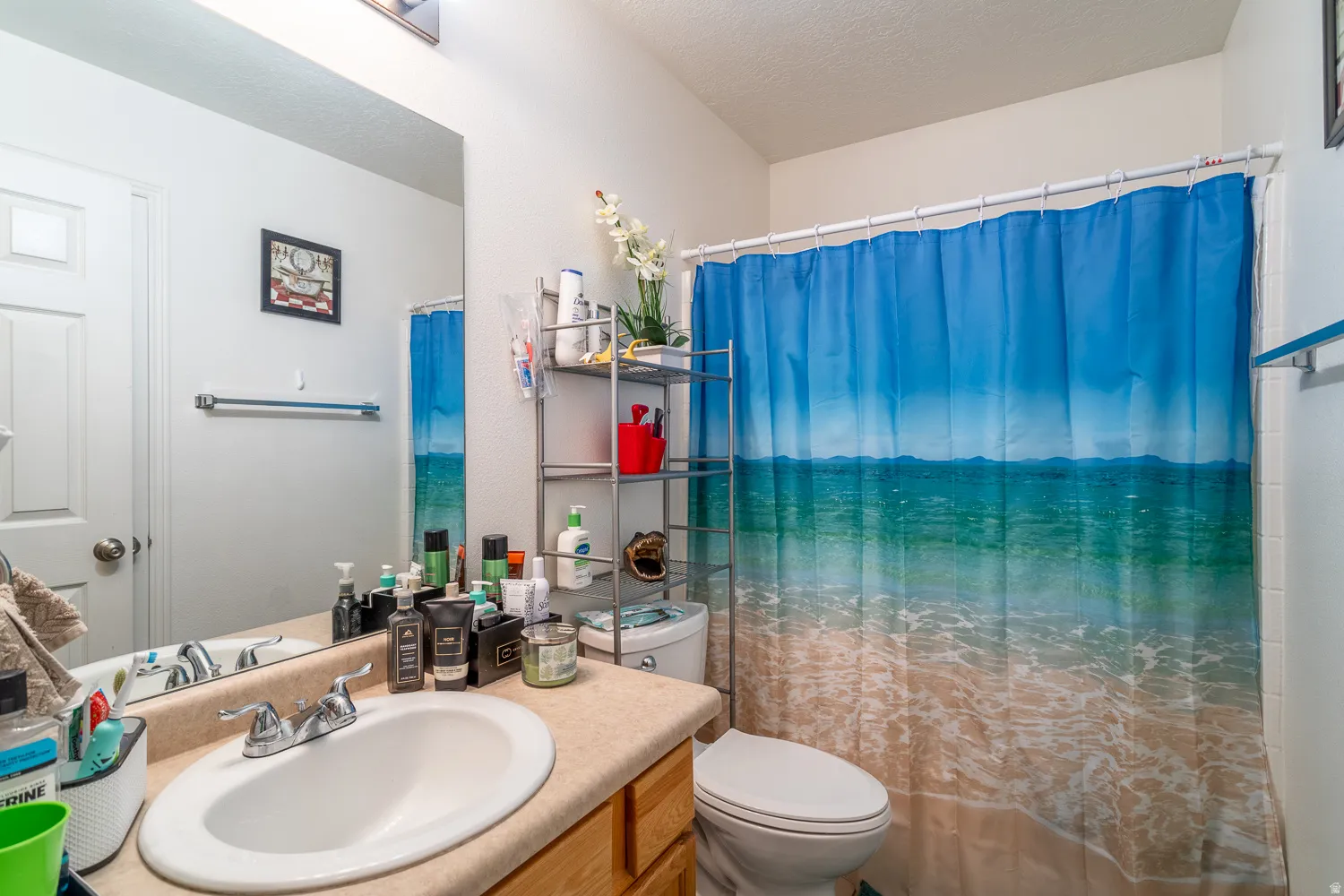 Bathroom featuring a single vanity with an integrated sink, chrome faucet, and light-toned countertop