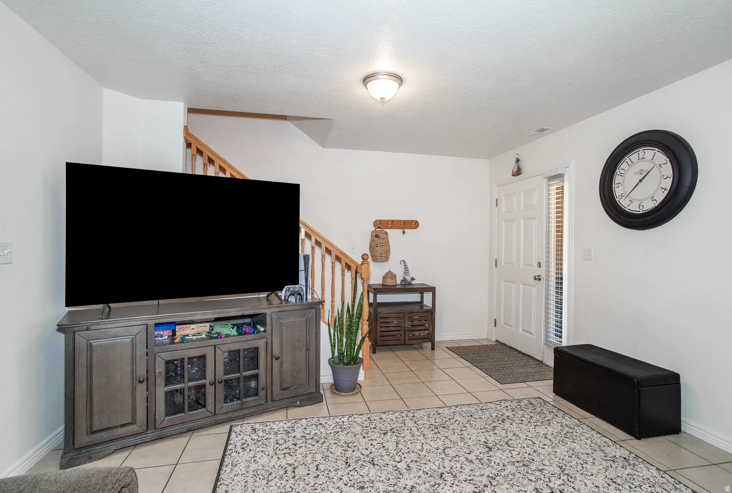 Tile flooring and white walls define this open entry area with a staircase featuring wood railings