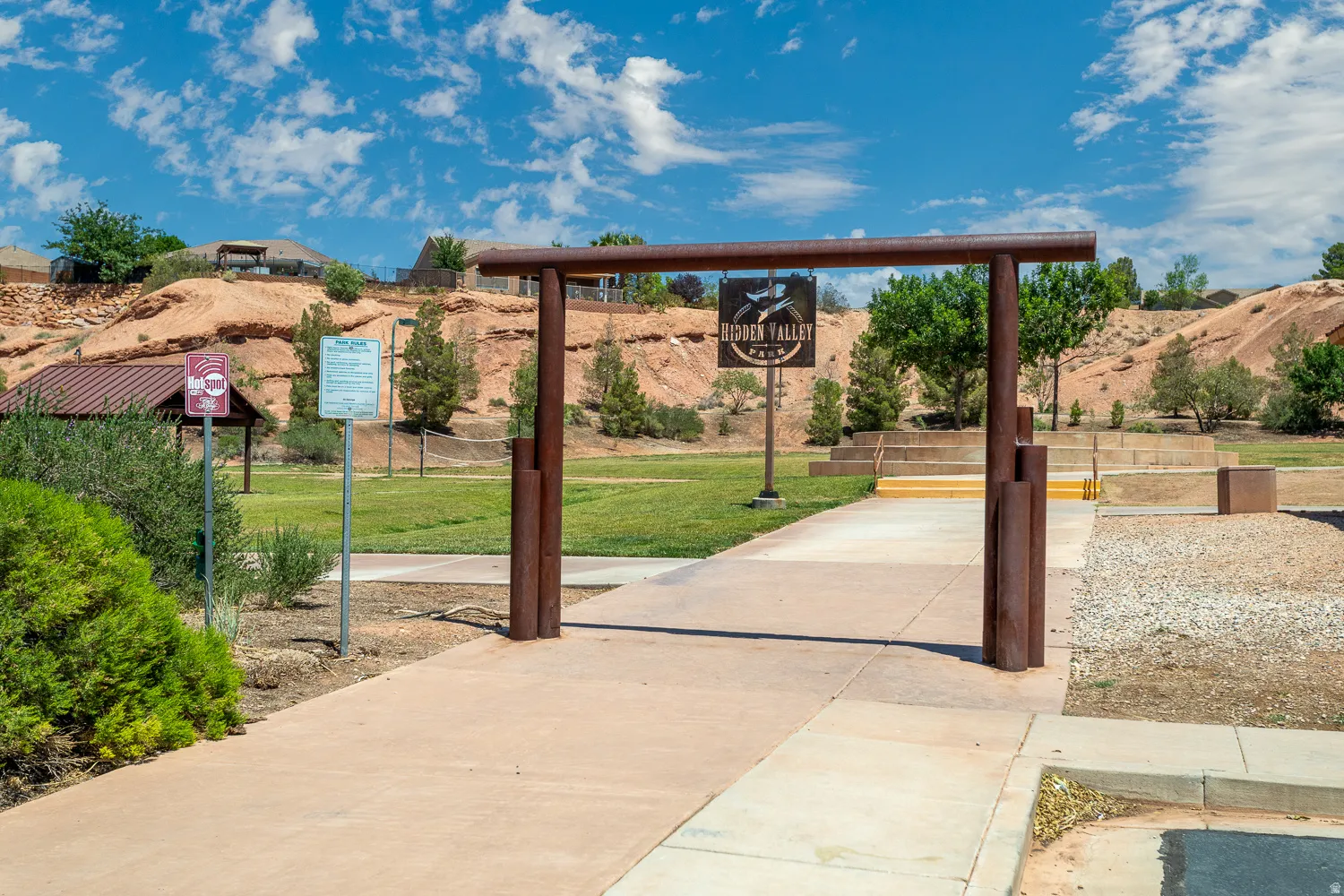 Park entry structure with a concrete pathway leading into a grassy area