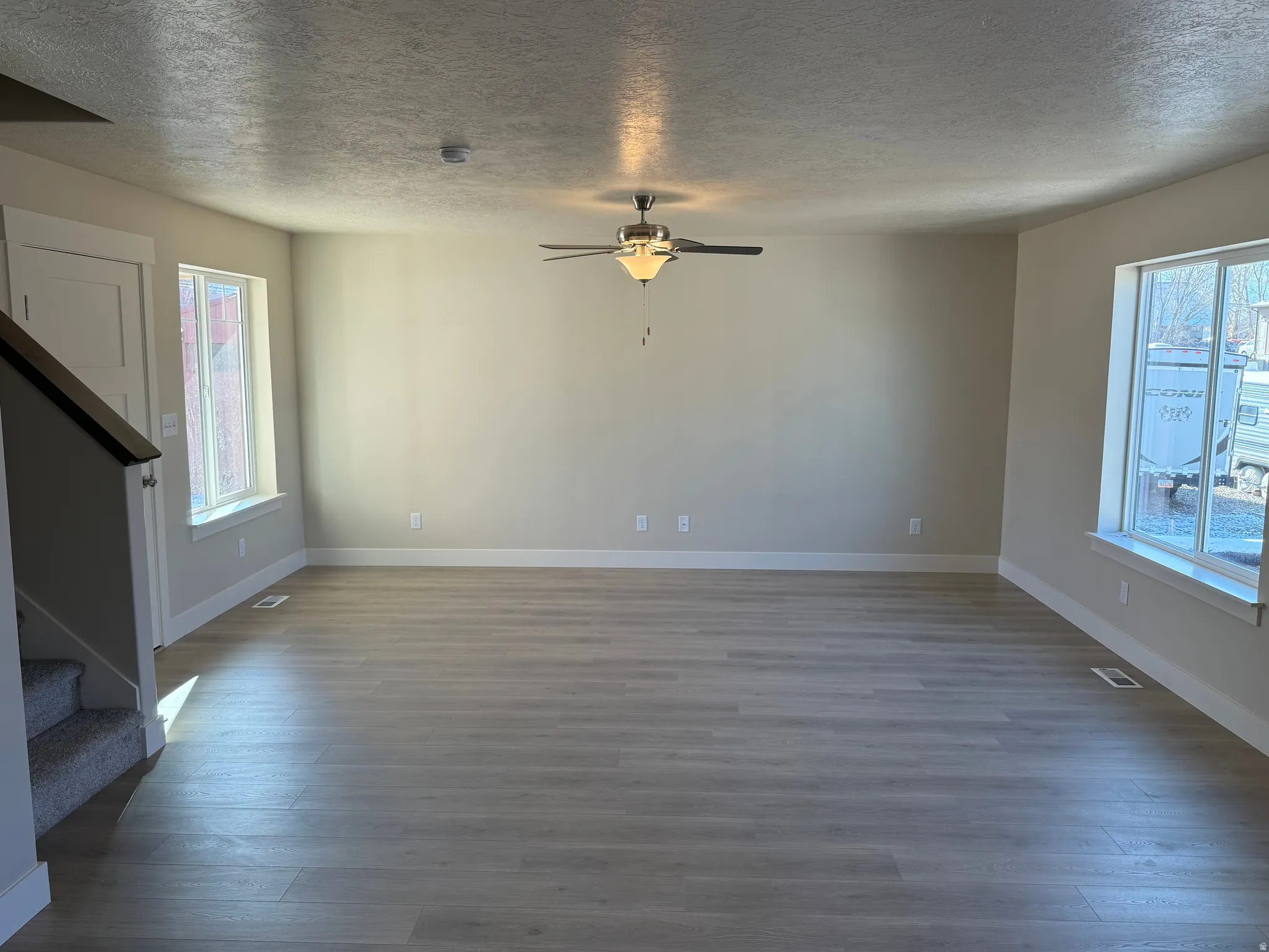 Spacious living area featuring light wood-finish flooring, neutral wall tones, and white trim throughout