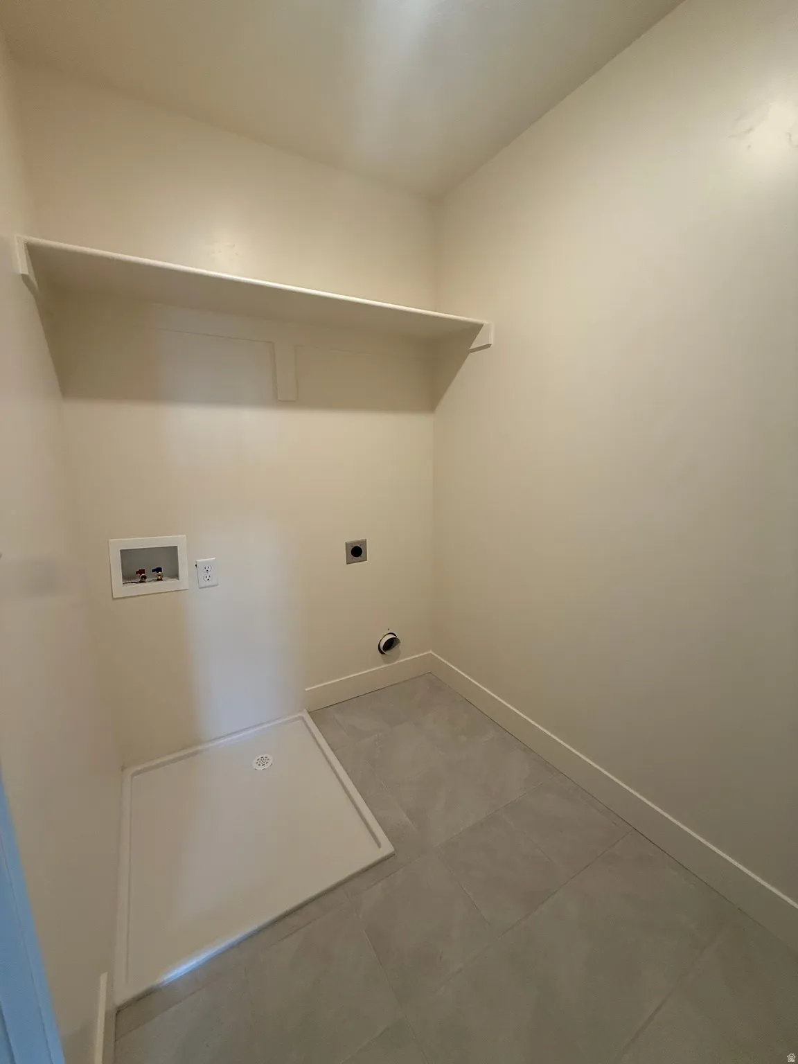Dedicated laundry area featuring a built-in shelf, plumbing hookups, and square tile flooring