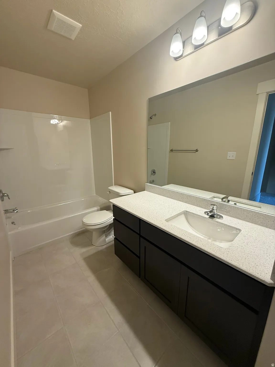 Bathroom featuring a dark wood-finish vanity with a light speckled countertop, an integrated sink, and a chrome faucet