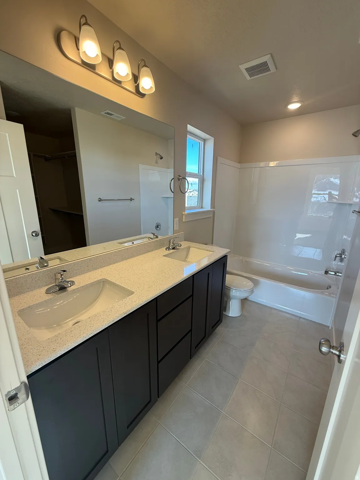 Spacious bathroom featuring a dual vanity with dark cabinetry and light-toned countertop