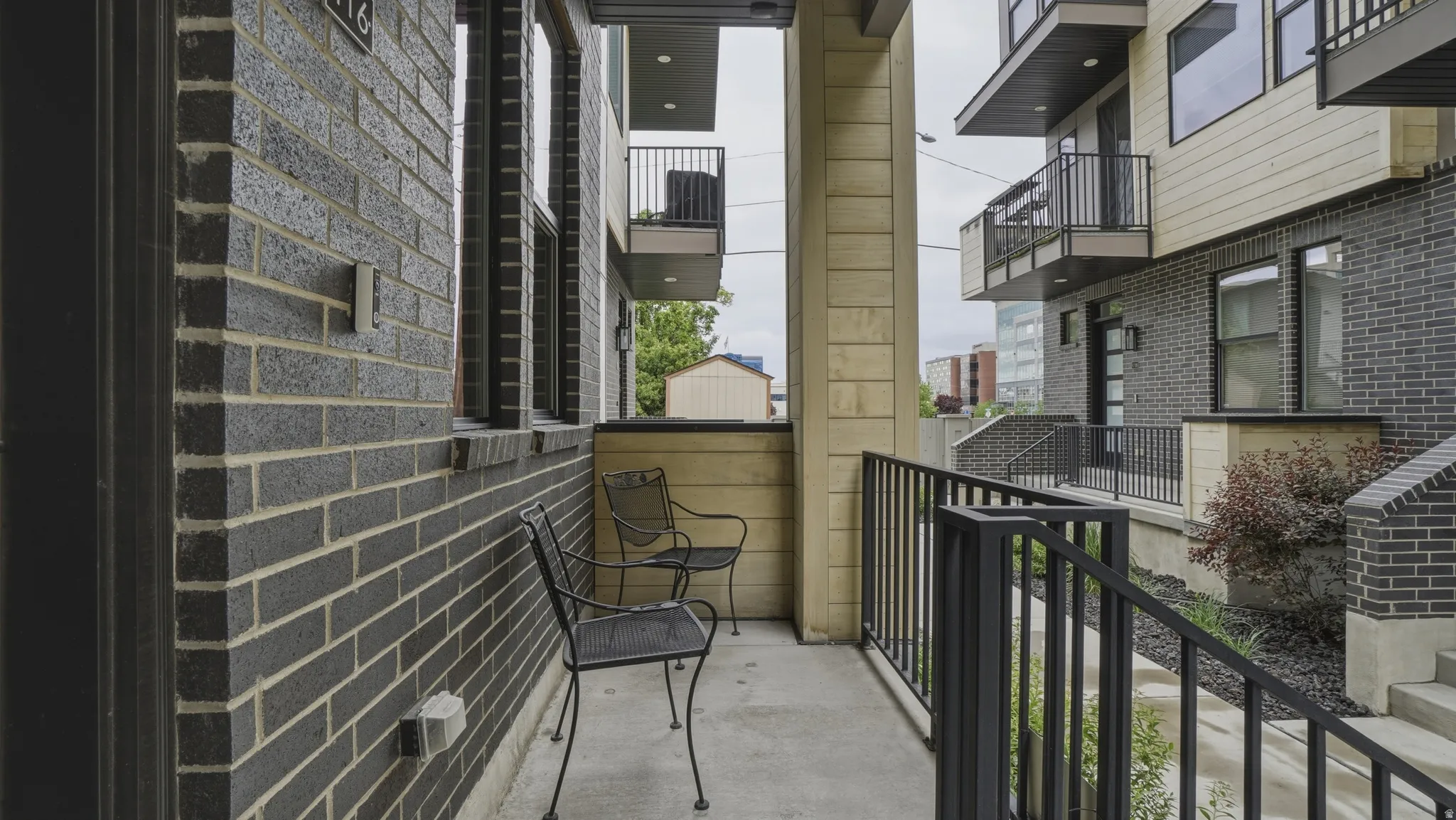 Private exterior patio area featuring dark brick facade, black metal railings, and a concrete surface