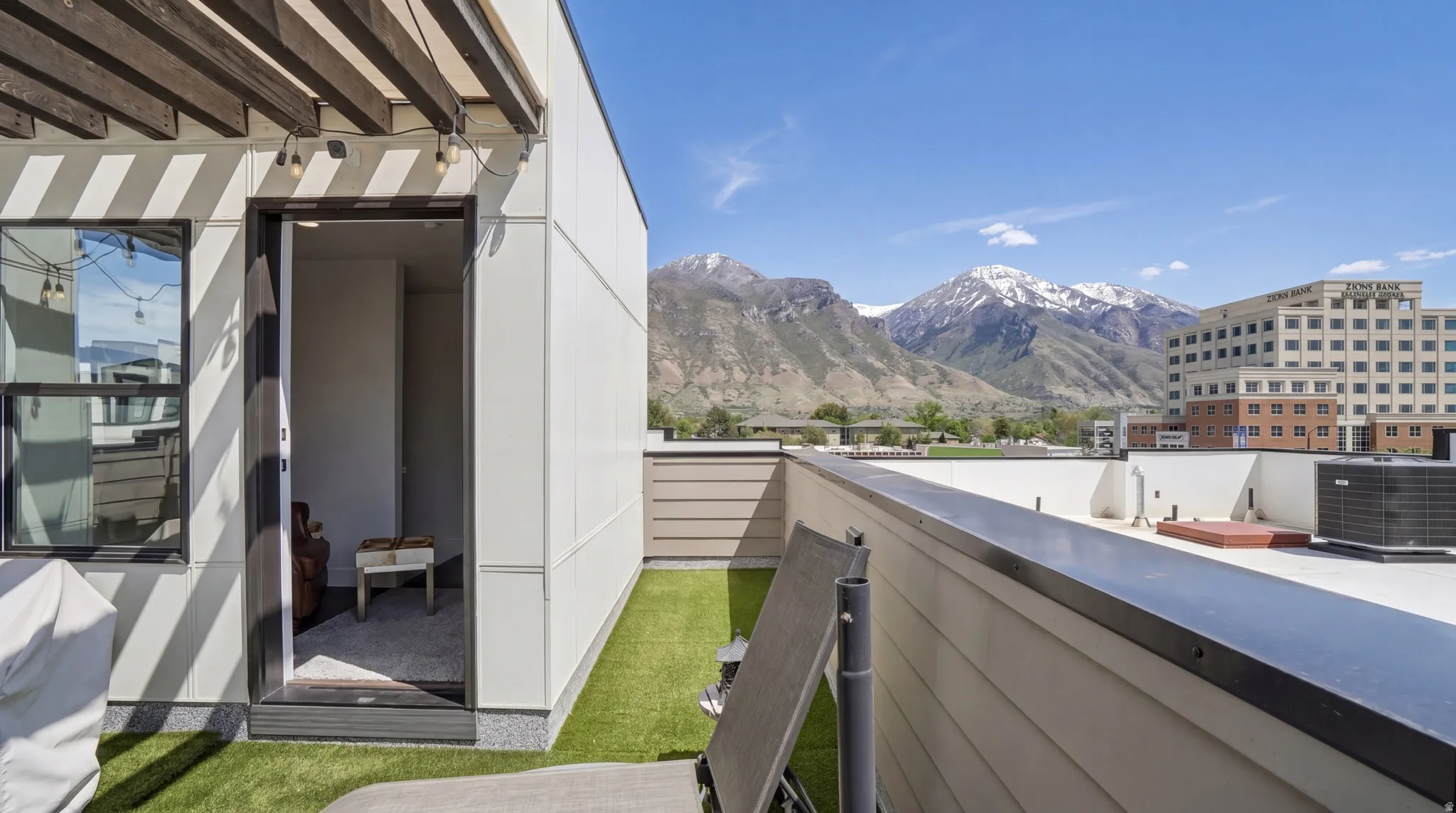 Rooftop patio featuring artificial turf, a pergola with string lights, and direct entry to interior space
