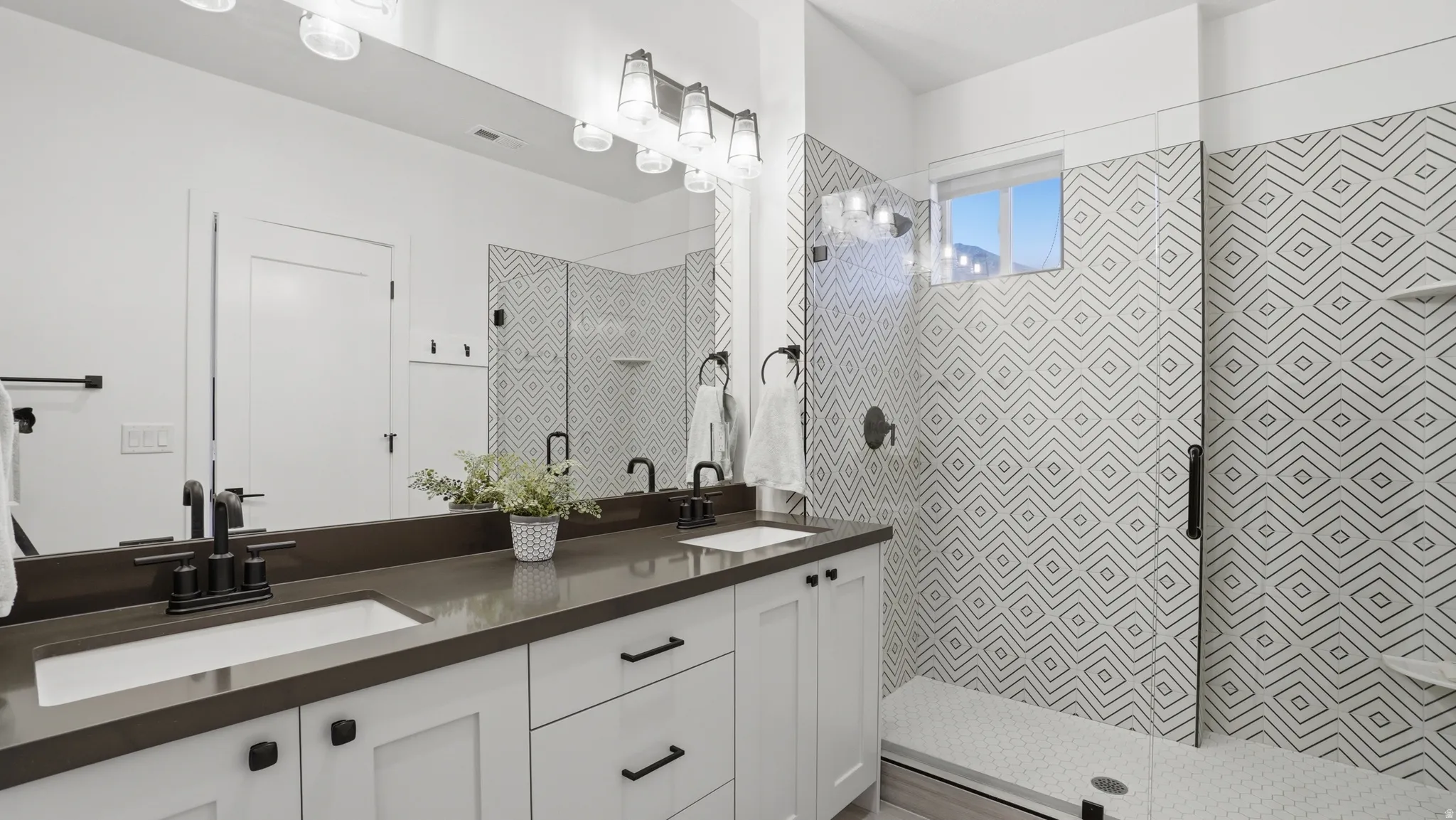 Dual vanity with a dark countertop and undermount sinks, featuring matte black fixtures and hardware