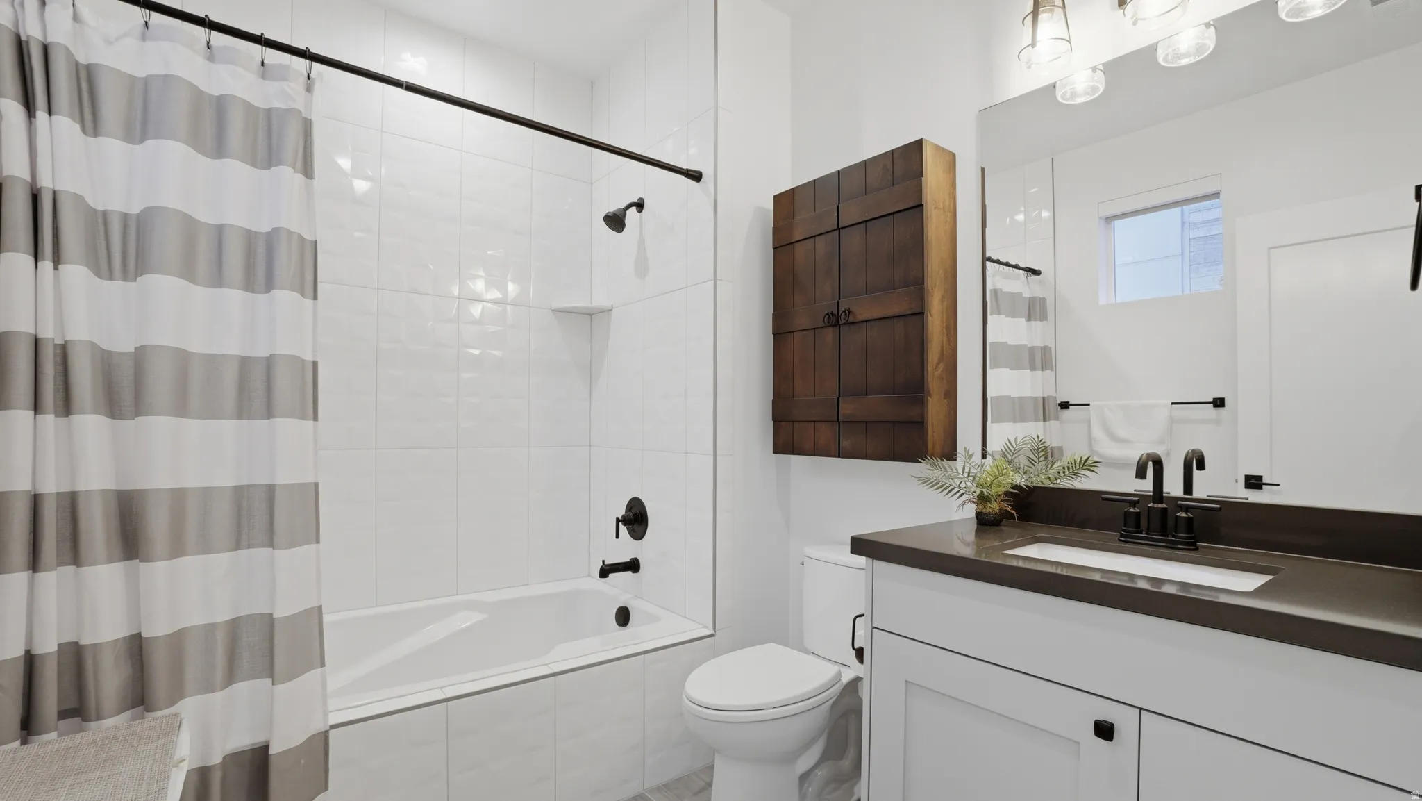 Contemporary bathroom featuring a white vanity with dark countertop, large mirror, and black matte fixtures