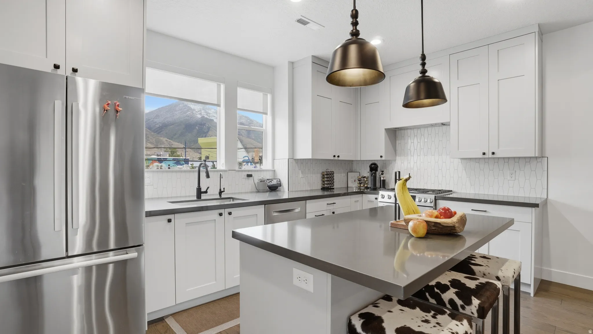 Spacious kitchen featuring white shaker cabinetry, dark countertops, a stainless steel refrigerator, and a tiled backsplash