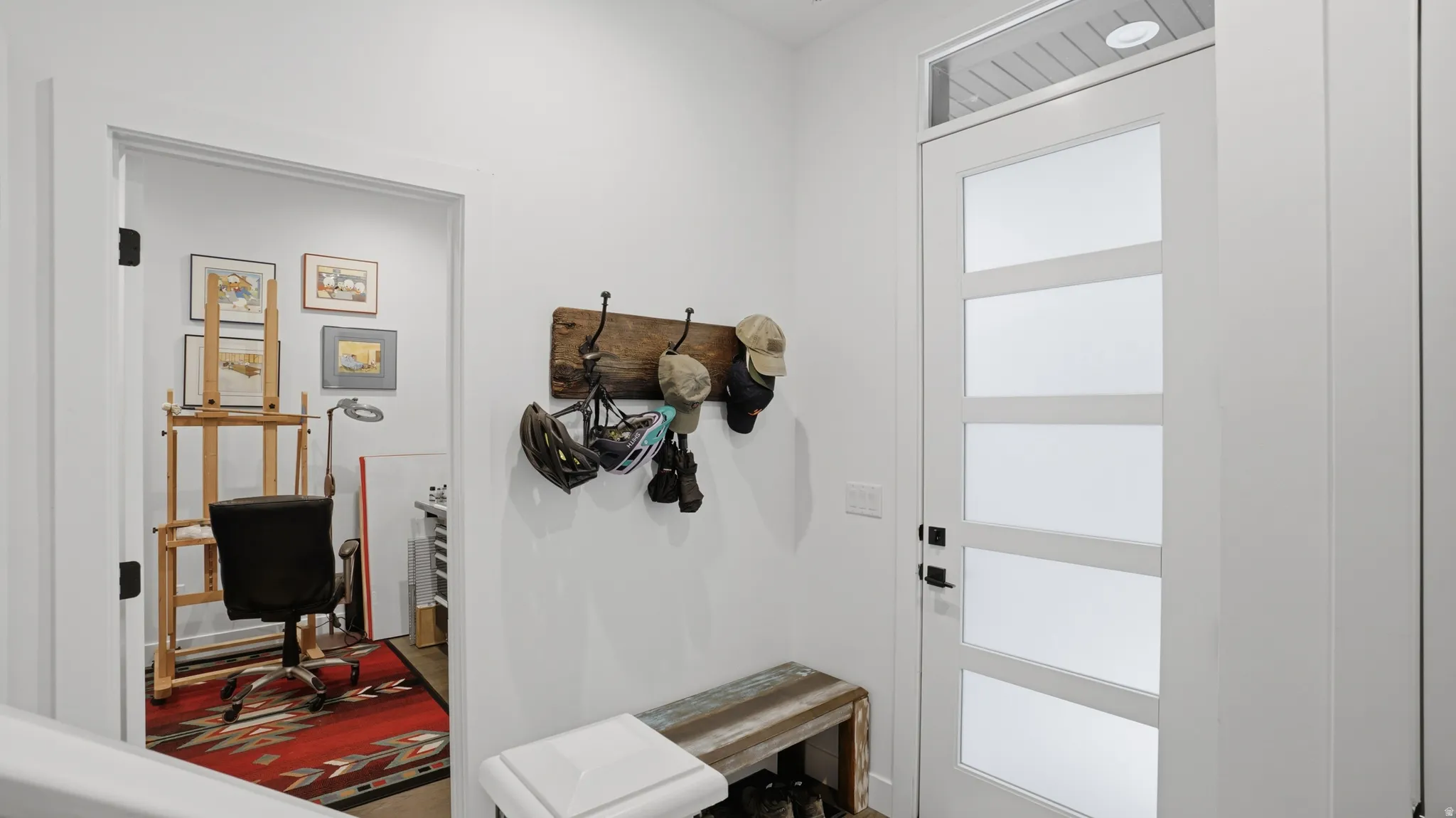 Entryway featuring a modern door with obscured glass panels and transom window, a built-in reclaimed wood bench, and a coat rack with dark metal hooks