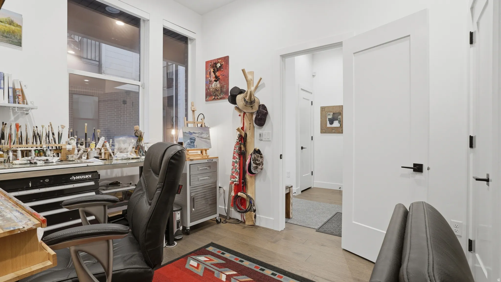Bright room featuring large windows, wood-finish flooring, white walls, and a modern flat-panel door with matte black hardware