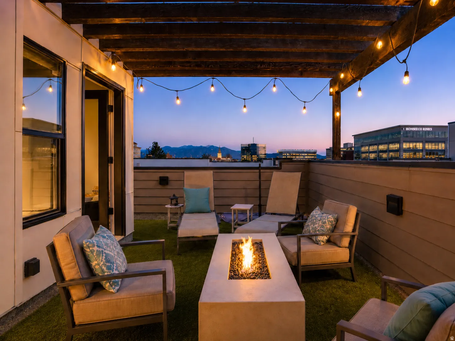 Rooftop deck featuring a wood pergola with string lighting, artificial turf flooring, and a built-in fire pit