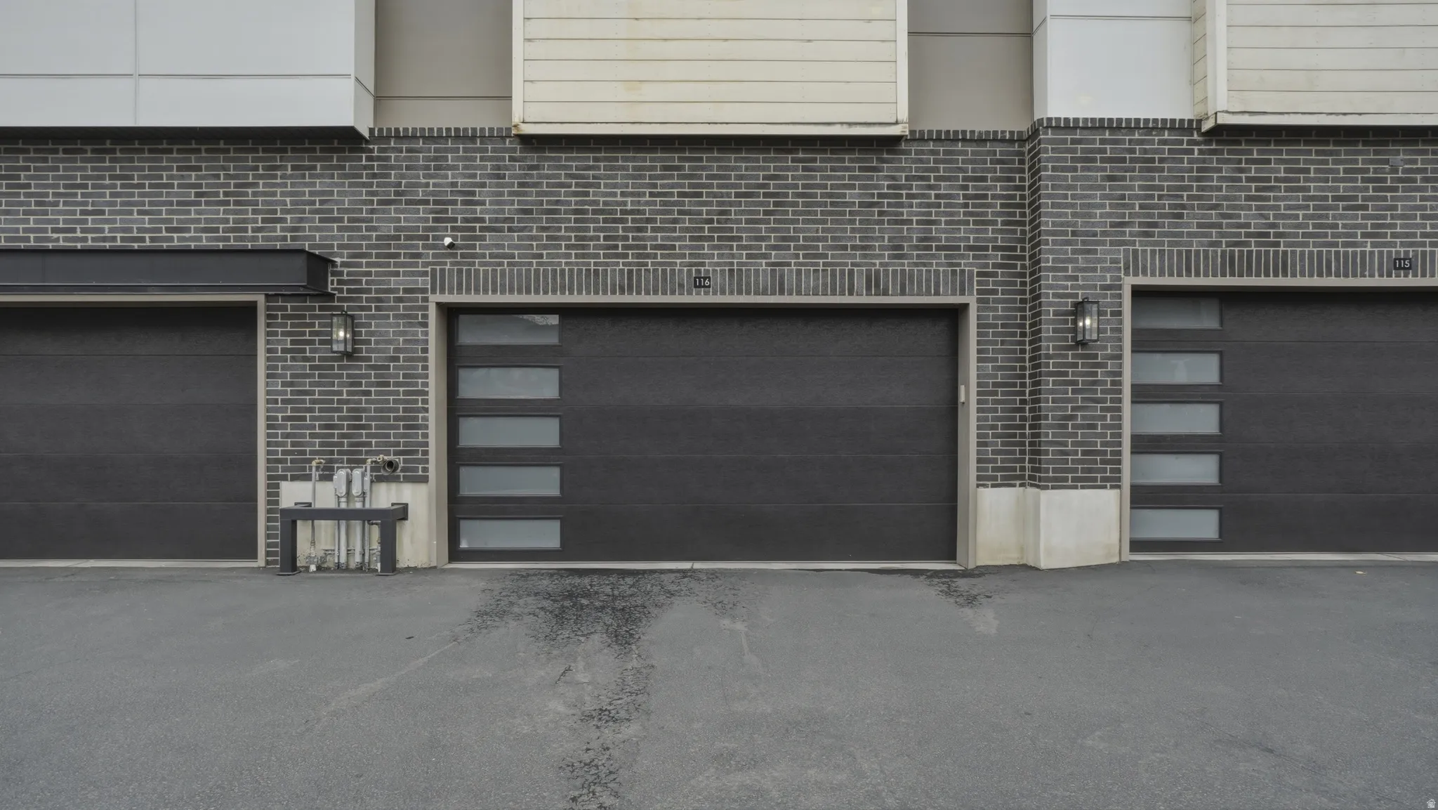 Modern garage doors set against a dark brick facade