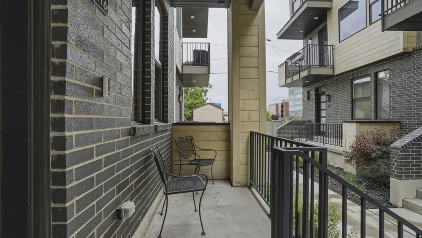 Private exterior patio area featuring dark brick facade, black metal railings, and a concrete surface