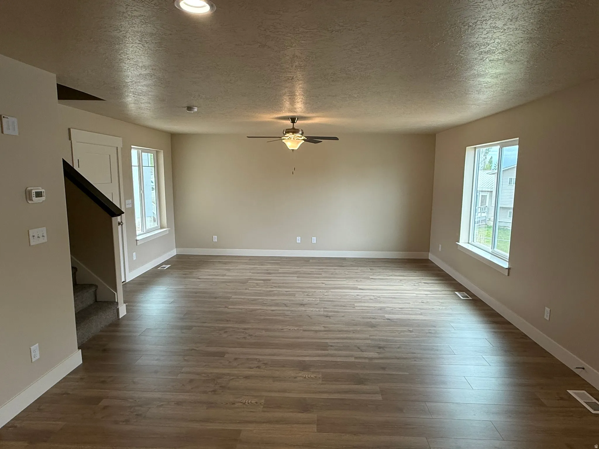 Spacious living area featuring wood-finish flooring, neutral wall tones, and white trim