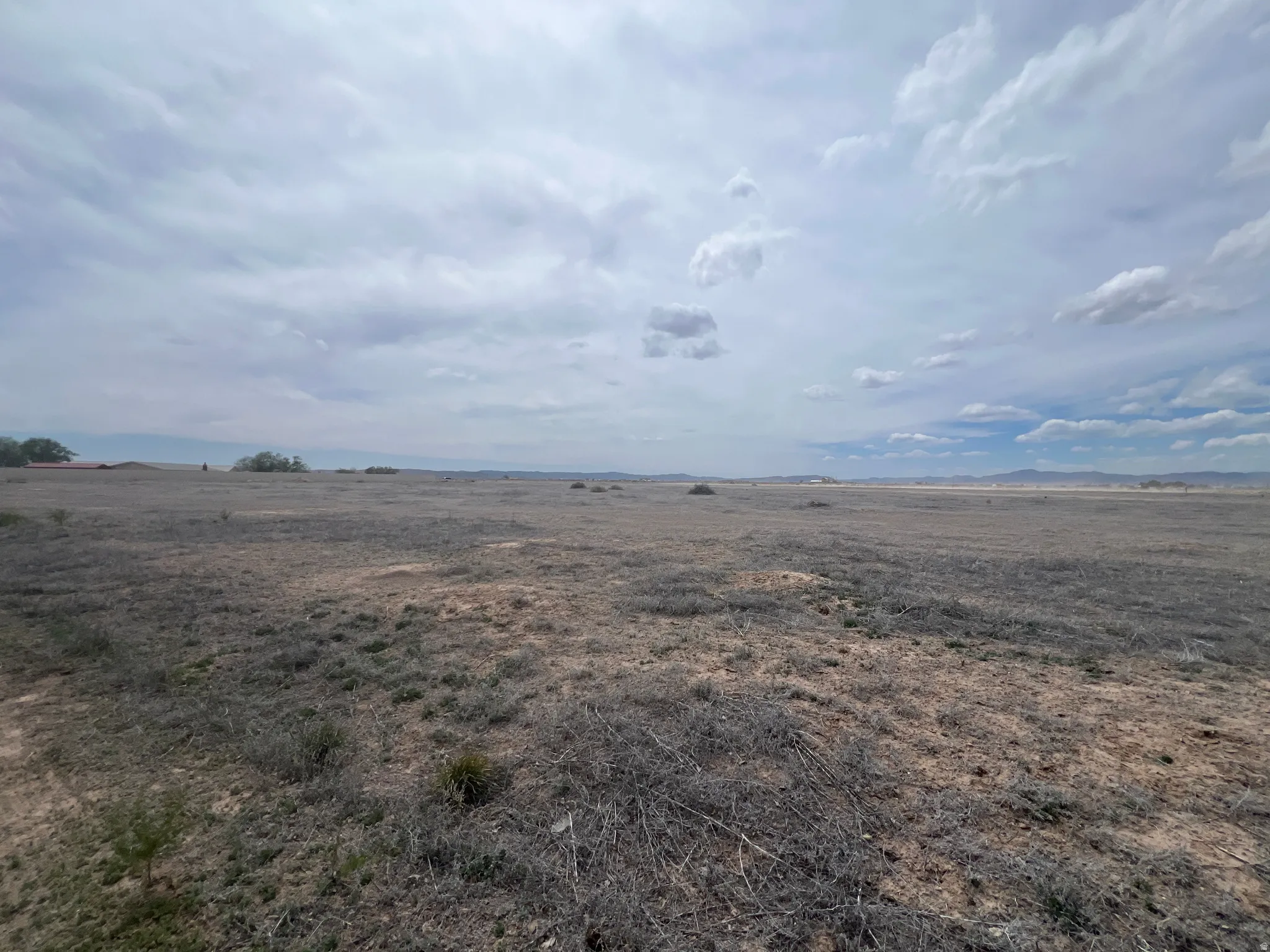 Expansive open land with varied vegetation and distant natural elements