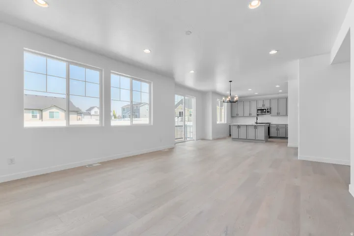 Expansive open-concept living area featuring light wood-finish flooring, recessed lighting, and large grid-pattern windows