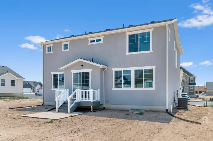 Two-story stucco exterior with white trim, featuring a ground-level patio and a raised deck with white railings