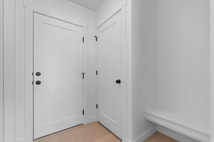 Light wood-finish flooring, built-in shelving, and two solid panel doors with matte black hardware