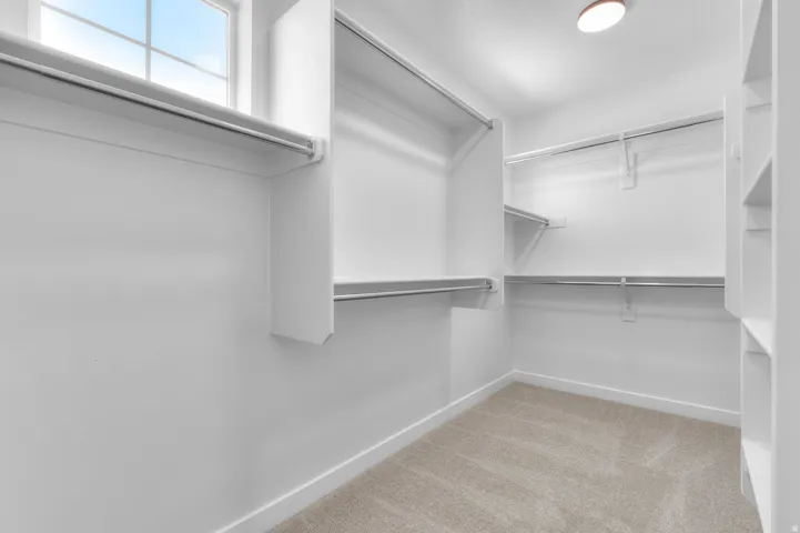 Walk-in closet featuring built-in shelving, hanging rods, an overhead light fixture, and a window