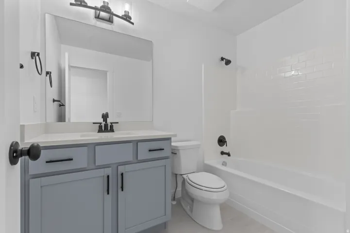 Bathroom featuring a single vanity with light gray cabinetry, a white countertop, and matte black fixtures