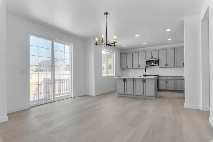 Open-concept living and kitchen area featuring wood-finish flooring throughout, recessed ceiling lighting, and a large center island with seating