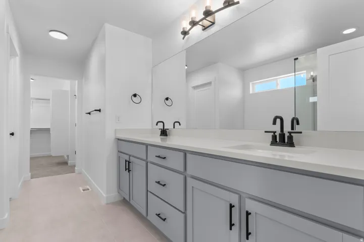 Dual vanity with light gray cabinetry, matte black hardware, and light-toned countertops
