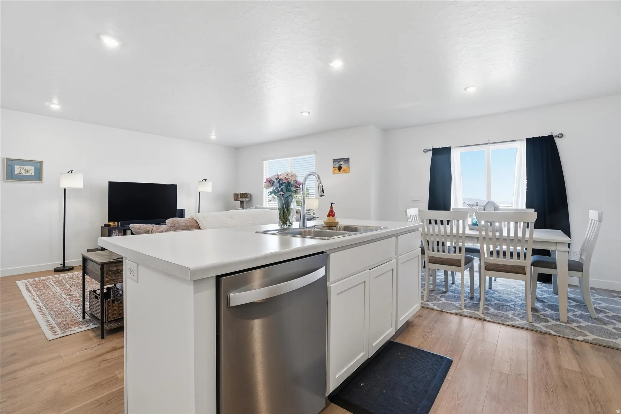 Bright kitchen island featuring a stainless steel dishwasher and undermount sink with a high-arc faucet