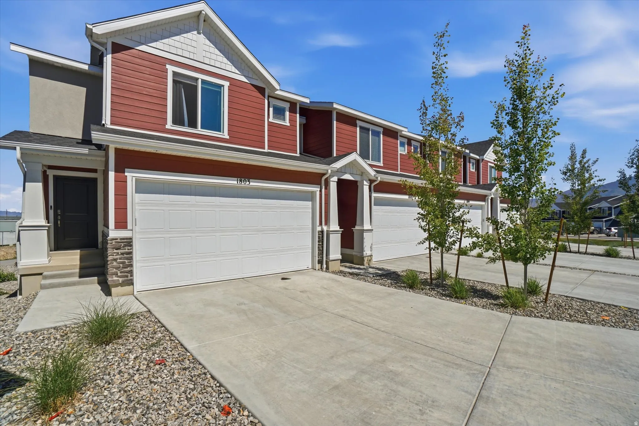 Contemporary townhome exterior featuring red siding, white trim, two car garage
