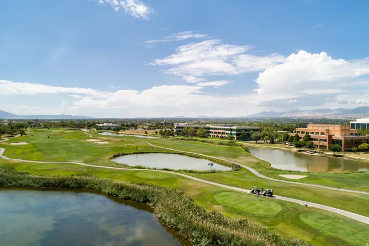 Expansive golf course landscape featuring multiple water hazards, manicured greens, and cart paths
