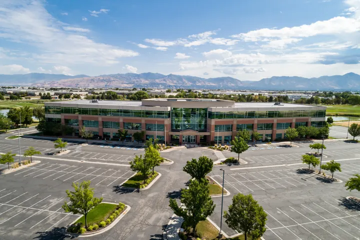 Modern commercial building featuring a curved glass facade and stone-finish lower level