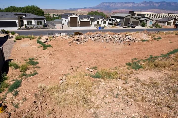 Expansive undeveloped lot featuring a red earth base and distant mountain backdrop