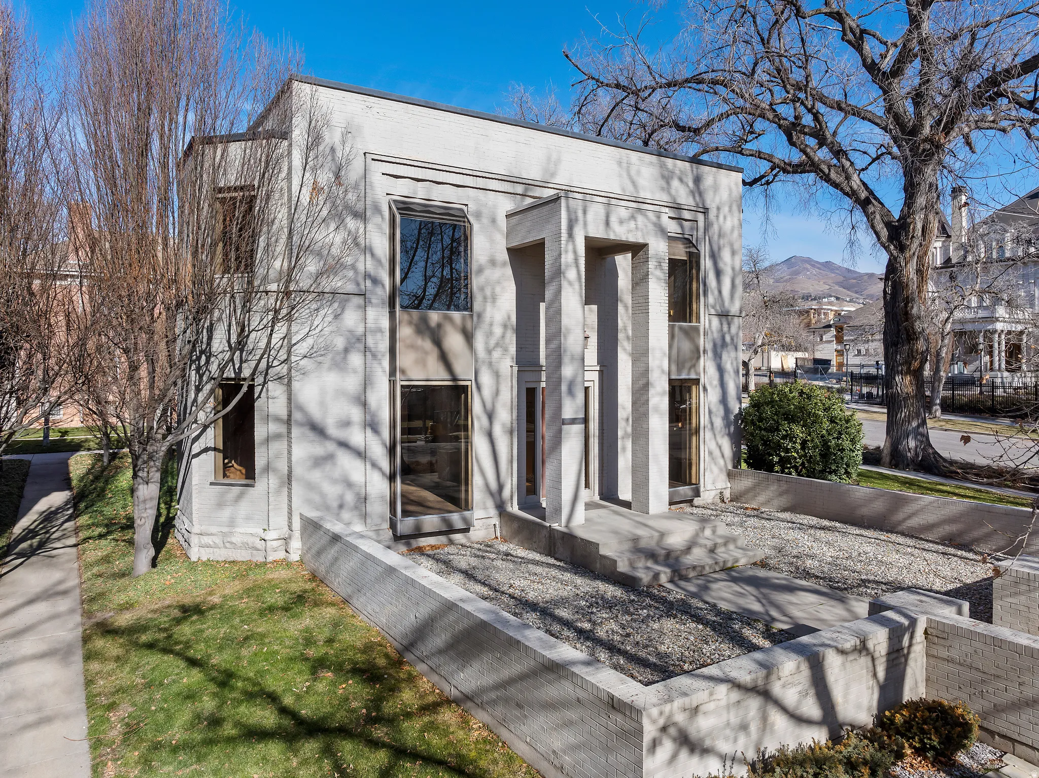 Modern facade with multiple large windows, a prominent recessed entry, and a mountain backdrop