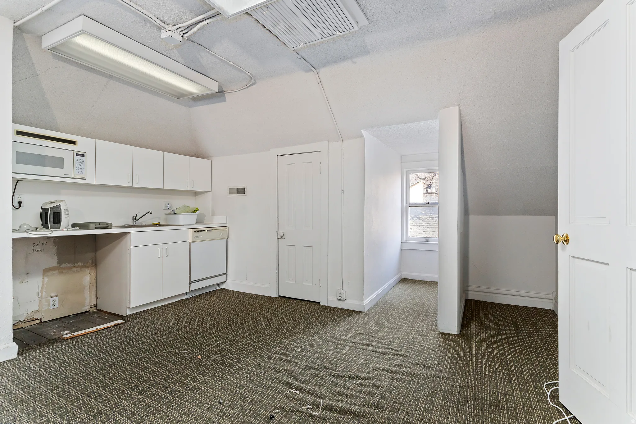 Kitchenette featuring white cabinetry, a built-in microwave, a sink, and a dishwasher