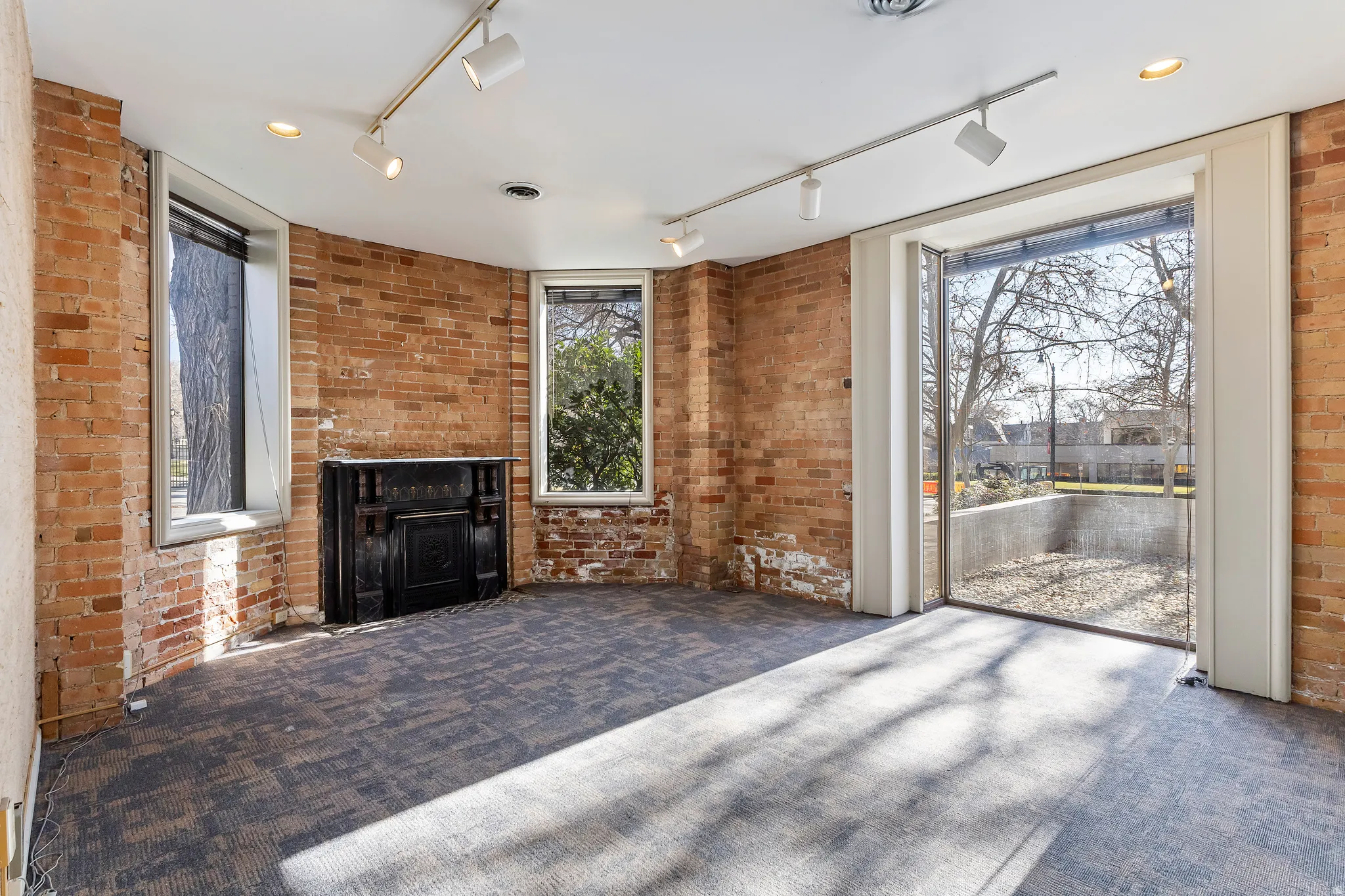 Exposed brick walls featuring a black decorative fireplace, multiple windows, and a large folding glass door