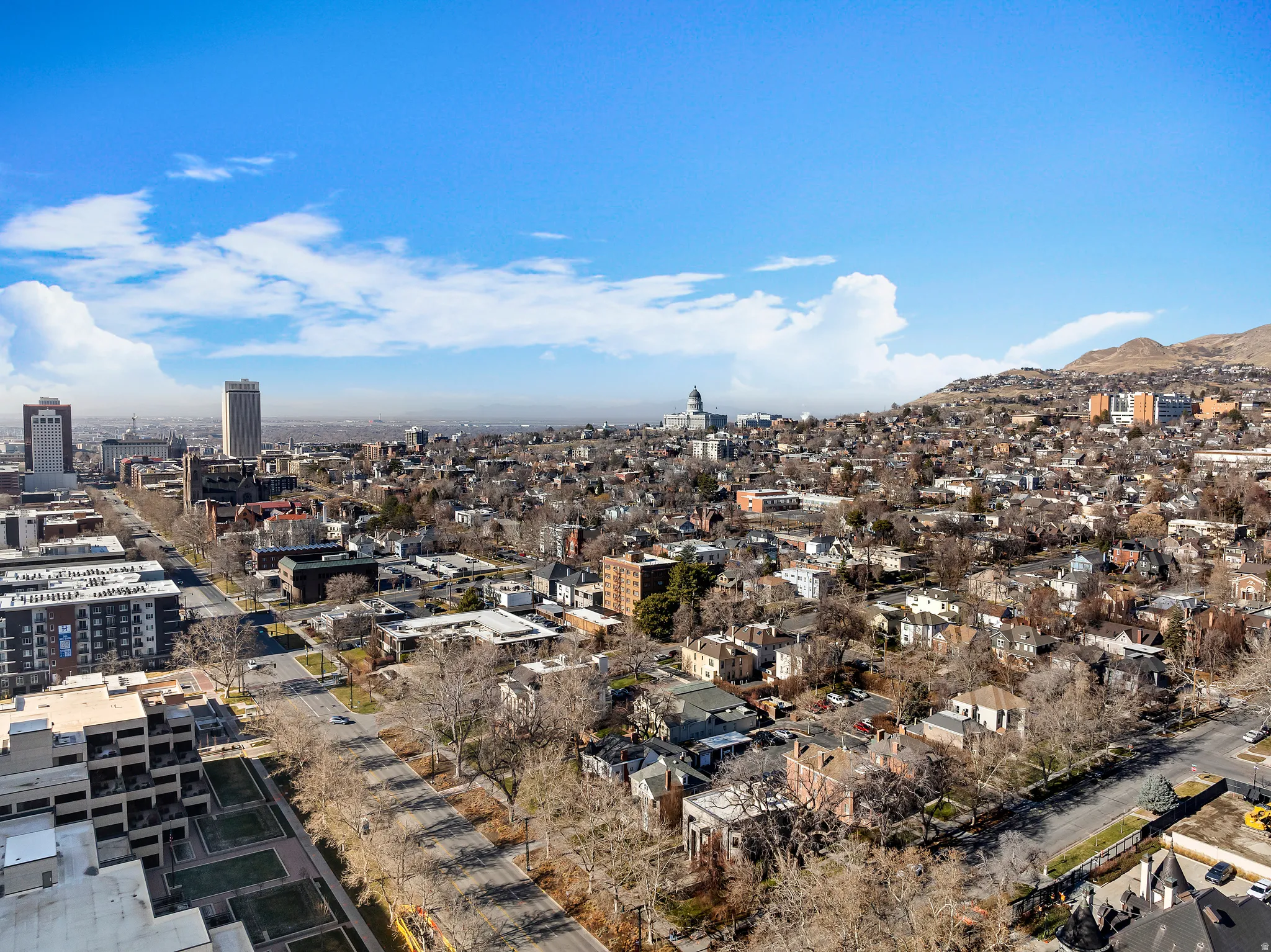Expansive urban skyline featuring commercial buildings, residential structures, and distant mountains